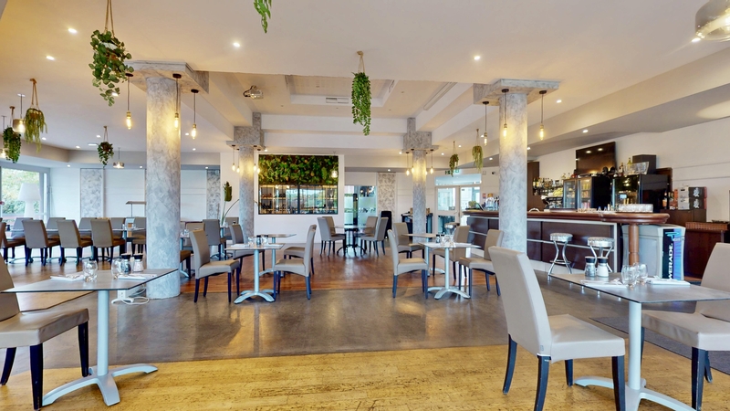 La salle du restaurant et son bar, colonnes claires et suspensions végétales