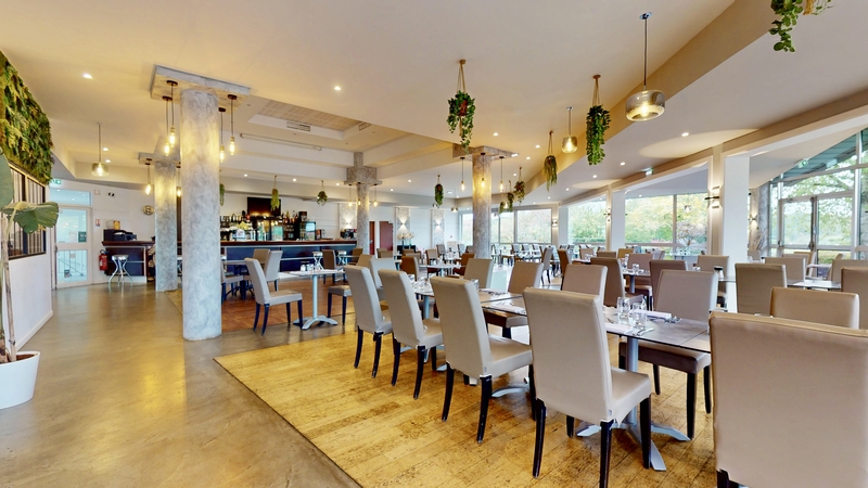 La salle de réception du restaurant du golf de Metz, tables dressées face aux baies vitrées, bar en arrière-plan