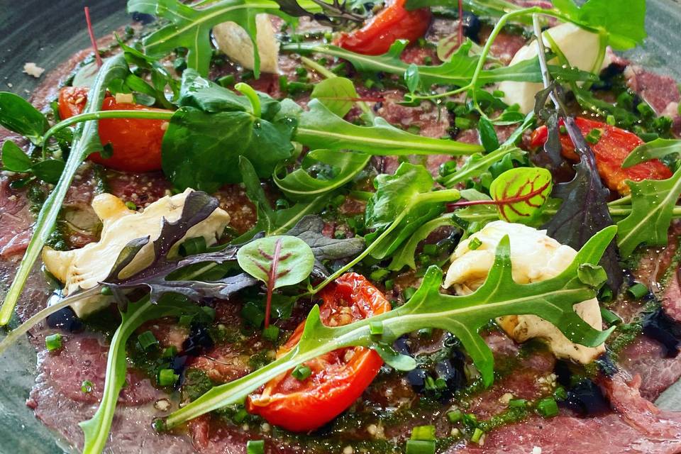 Carpaccio de bœuf, roquette, tomates confites et copeaux de parmesan